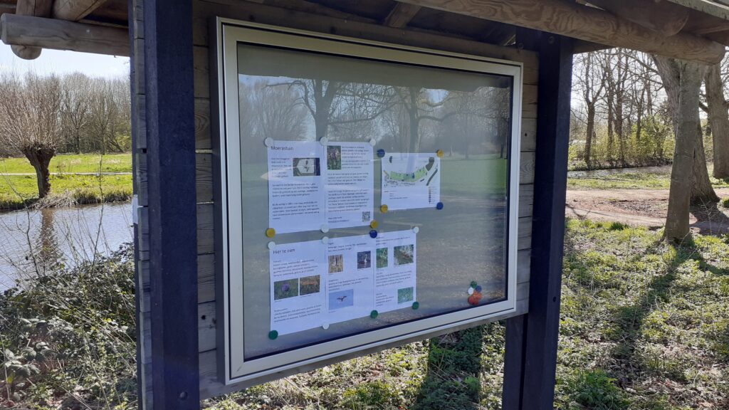 Vitrine met daarin informatie over de moerastuin. Er is een stevig houten dak boven.