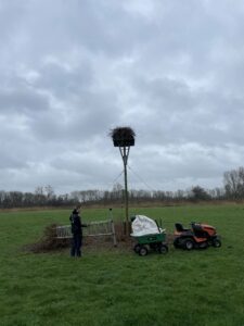ooievaarsnet in weiland met persoon en mini tractor met aanhanger
